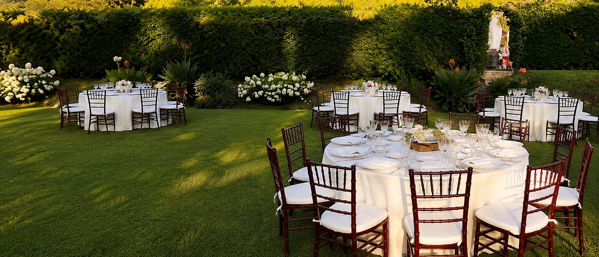 Il giardino fiorito con le tavole apparecchiate, nella luce del pomeriggio
