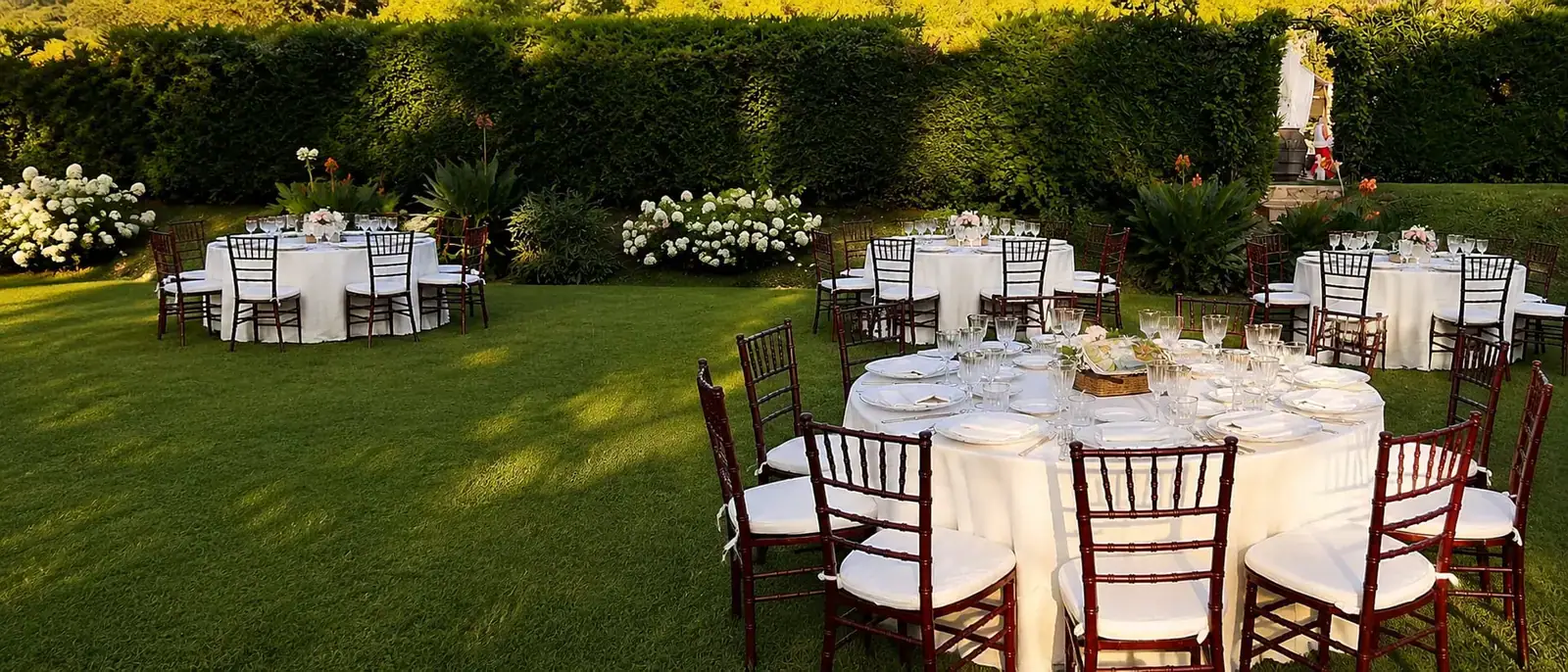 Il giardino fiorito con le tavole apparecchiate, nella luce del pomeriggio
